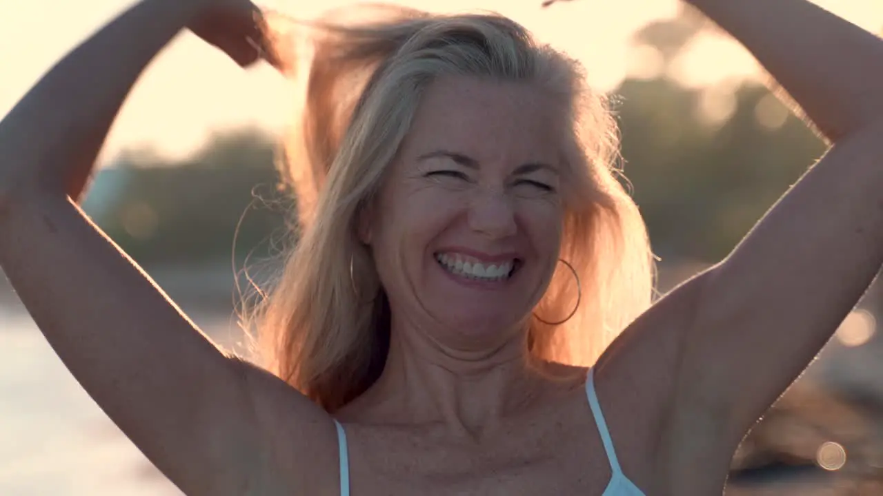 Beautiful backlit woman looking to the sky putting her arms out and looking carefree while being on a tropical beach