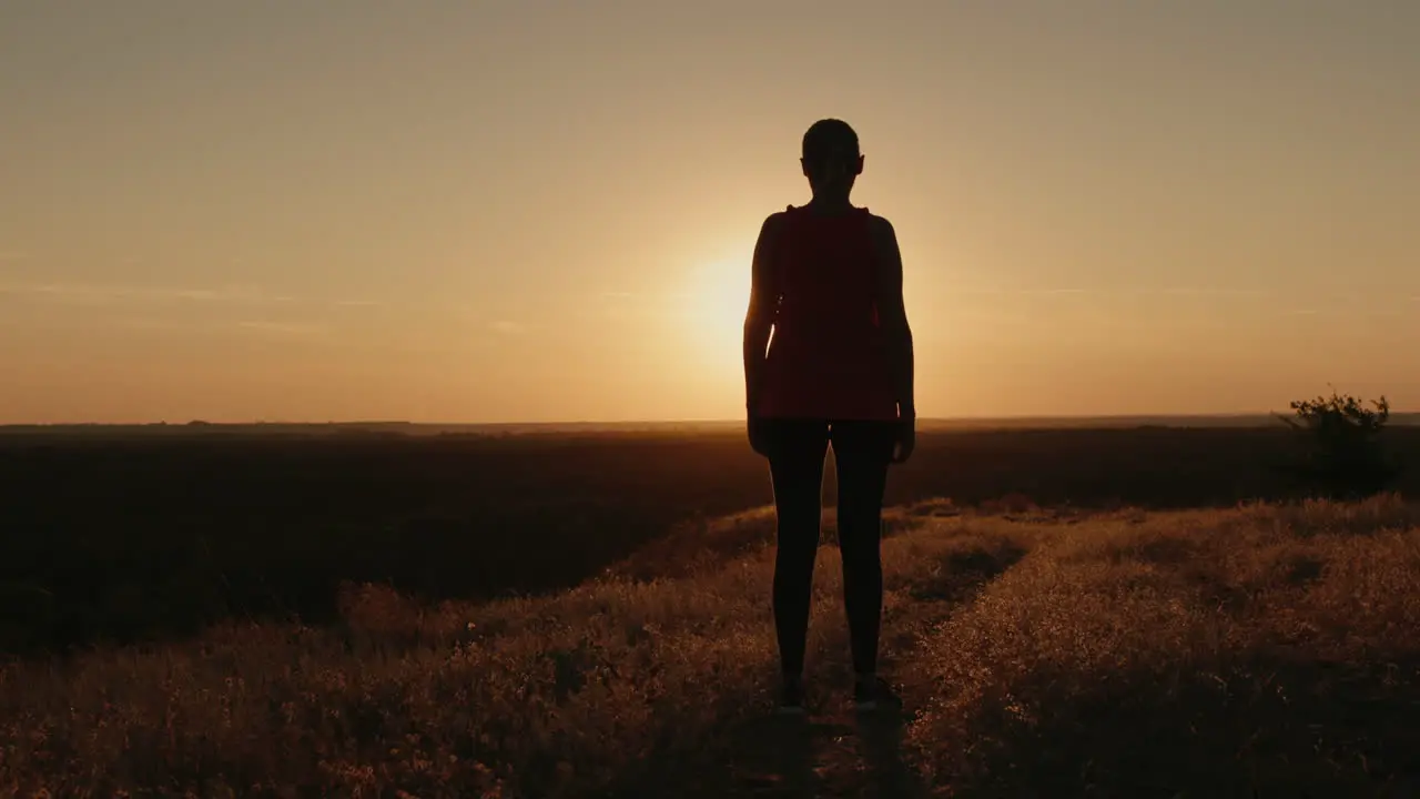 Slender woman silhouette in the setting sun