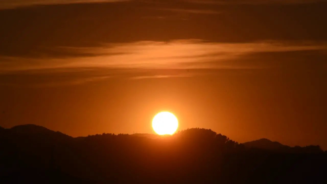 Sun setting slowly over the forest with clouds above