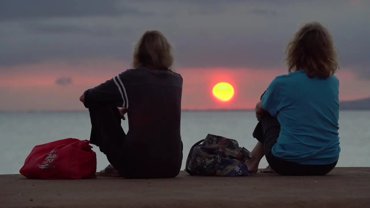 Two women watch sunset at Ala Moana Beach Park in Honolulu Hawaii