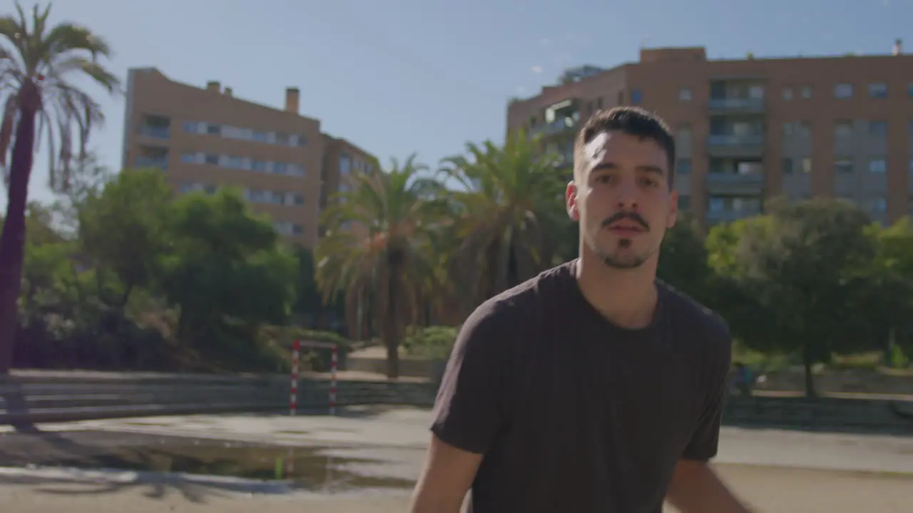 Close-up of a young Caucasian playing basketball on a street court looking at the camera and hesitating to dribble you with the ball