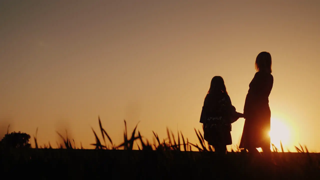 Silhouettes In Full Growth Of Mother And Daughter They Stand In A Picturesque Place At Sunset Happy 