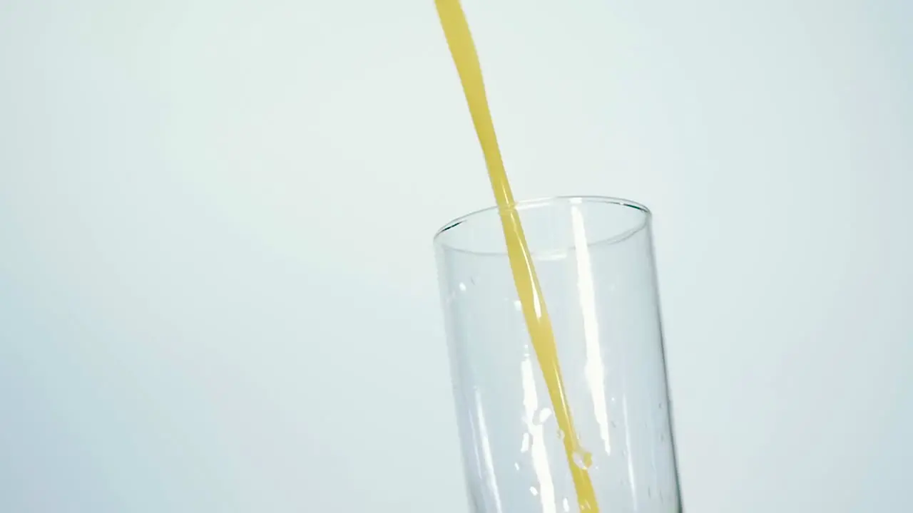 Slow Motion Shot of Fresh Orange Juice Being Poured in a Glass on white background Close up Shallow depth of field