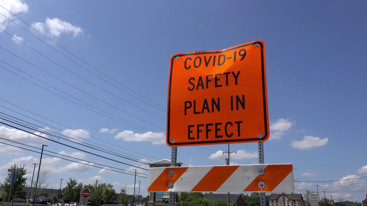 A COVID safety sign with traffic passing by