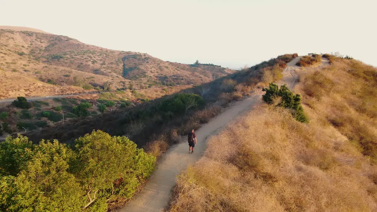 Drone shot of a solitary hiker walking up a trail