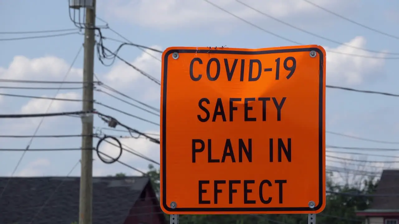 COVID safety sign with utility wires and buildings in background