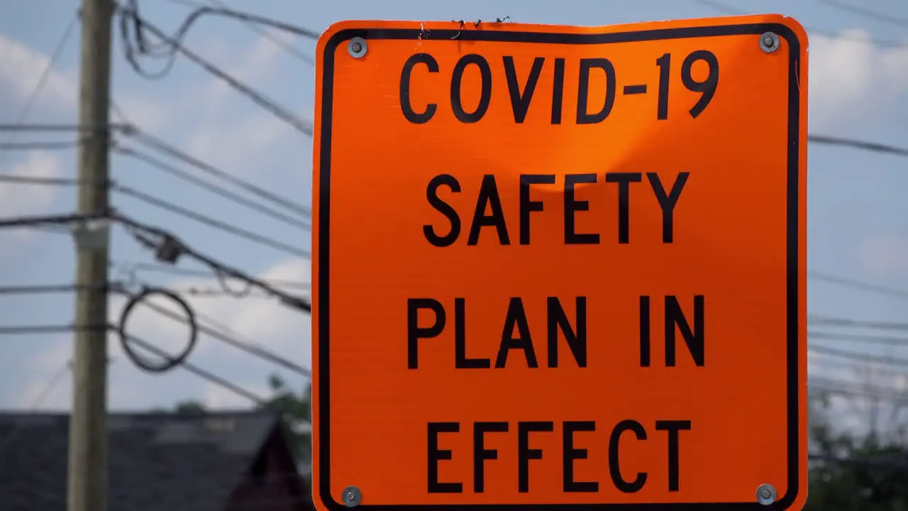 COVID safety sign in safety orange stands roadside