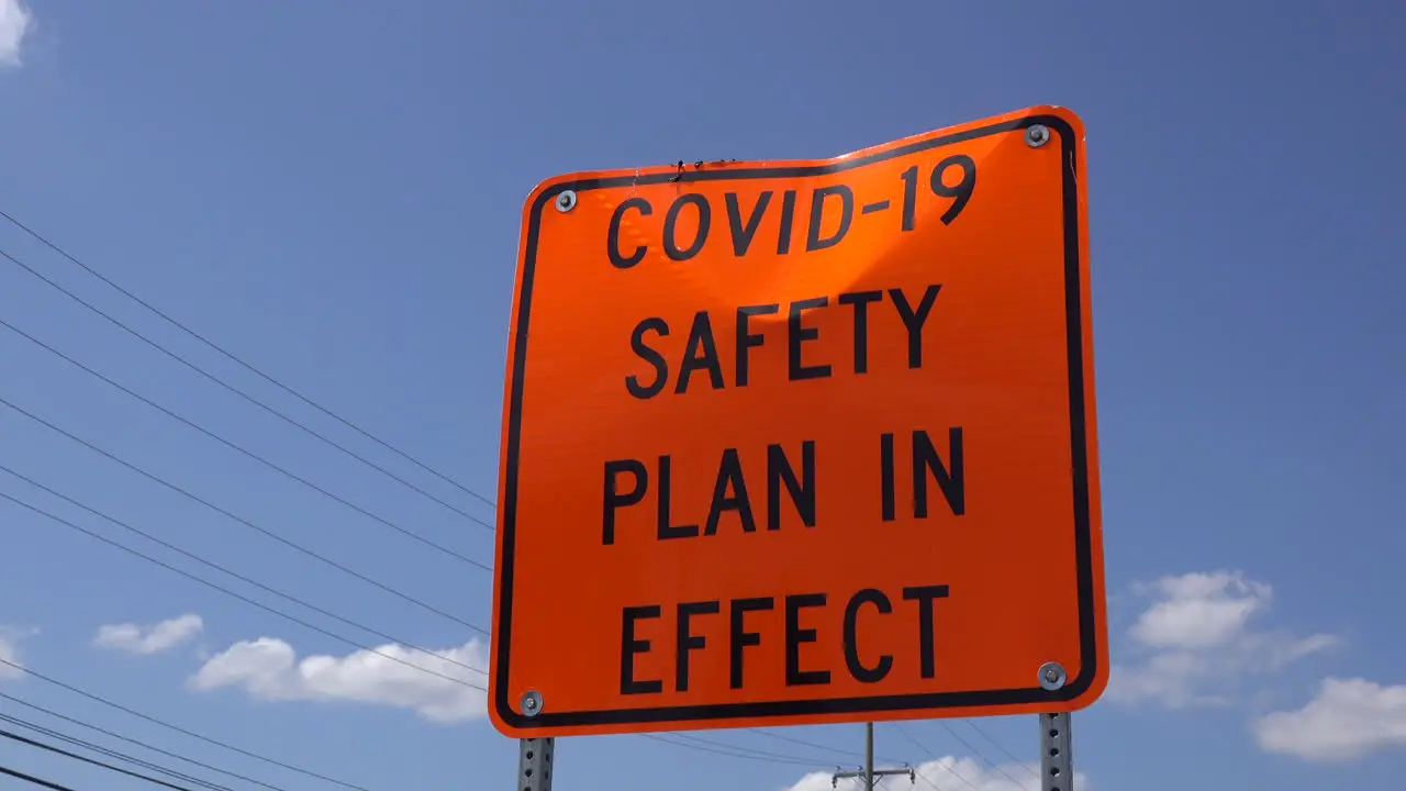 A dented COVID safety sign seen from a low angle