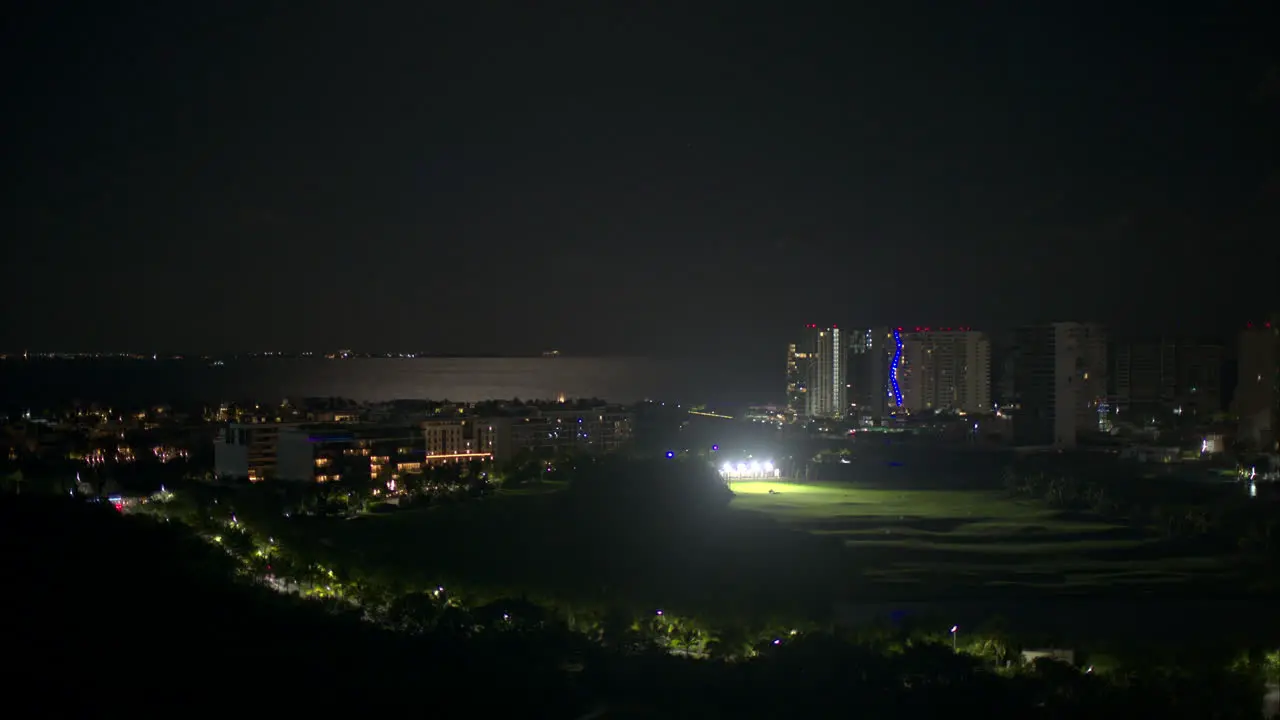 Aerial view of the golf range in Puerto Cancun at night with the caribbean sea behind and isla mujeres