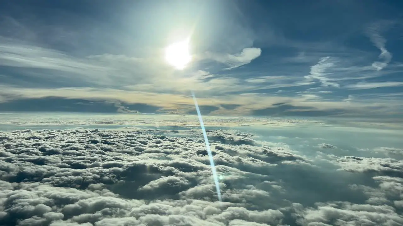 Beautiful flight scene while flying at creuise level over layers of clouds and with a sunbeam reflected in the cockpit window