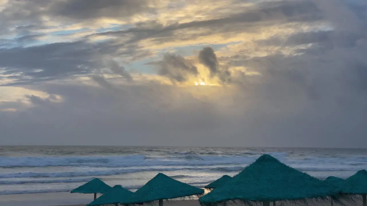 Waves breaking in a beach with amazing sunset with some empty blue straws