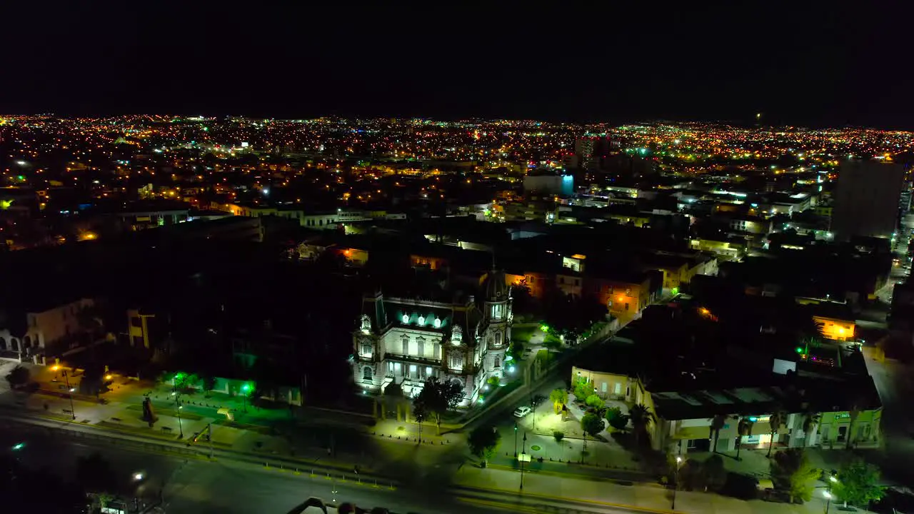 Aerial view around the Quinta Gameros building with night lights in Chihuahua city Mexico orbit drone shot