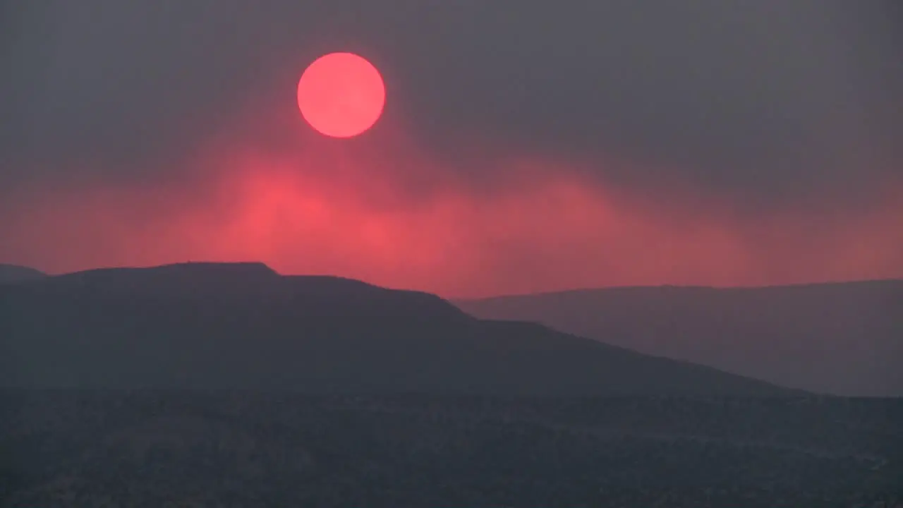 Time lapse shot as the sun sets behind a smoky red horizon