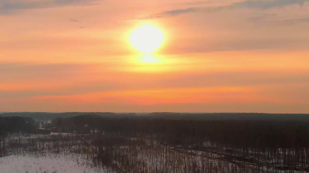 Colorful pink sunrise in winter over leafless trees aerial dolly out