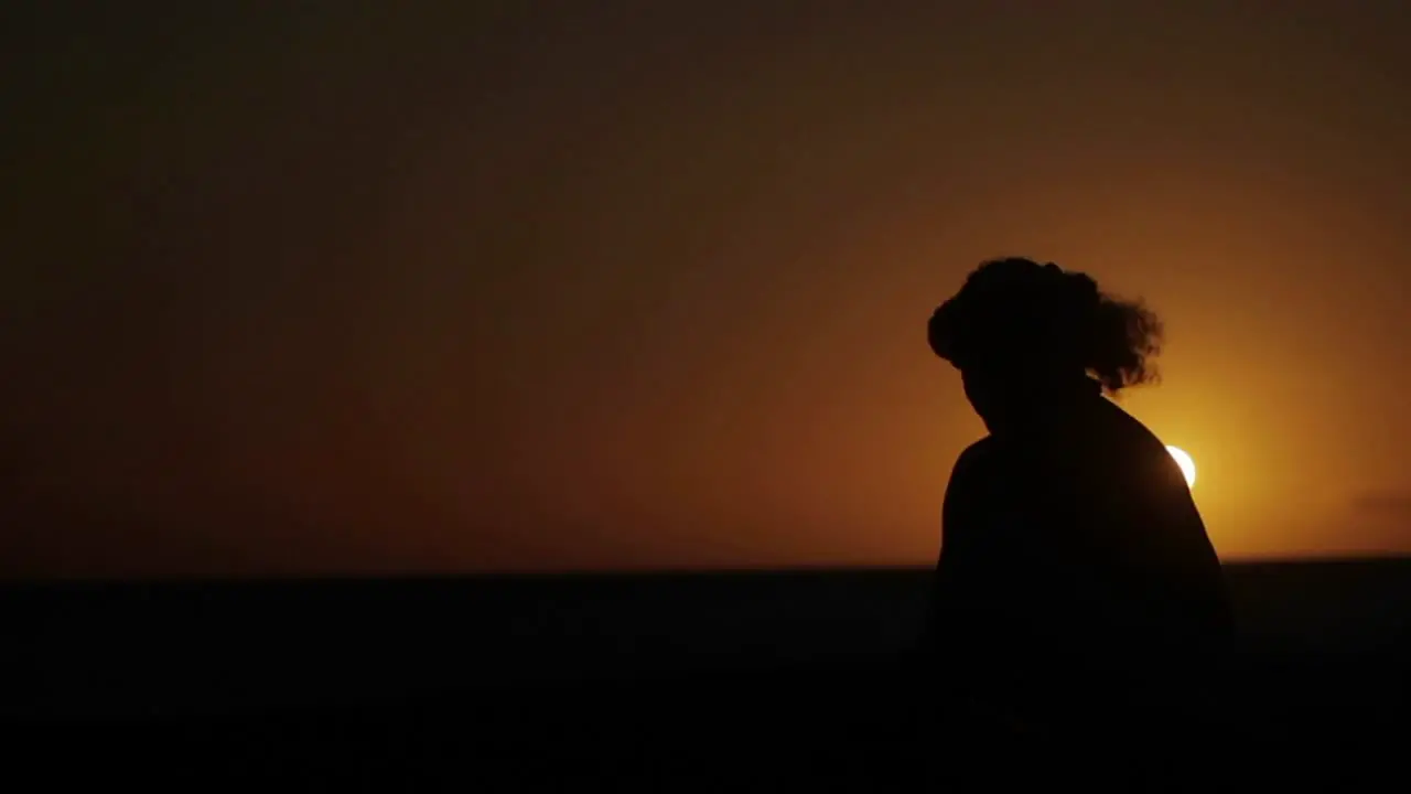 A Hawaiian man performs a traditional dance in front of the sunset