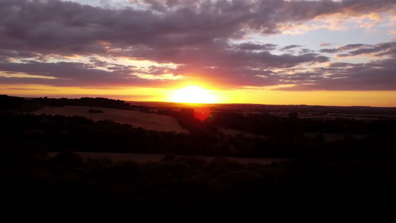 Moving away from a stunning sunset sky aerial shot over fields in Hitchin Hertfordshire England Uk