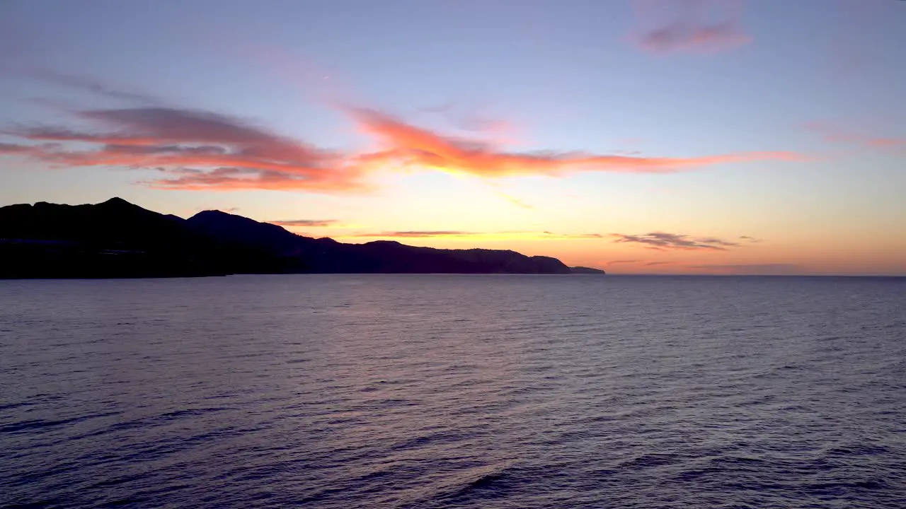 Calm and relaxing view toward ocean at sunset with mountain silhouette in background