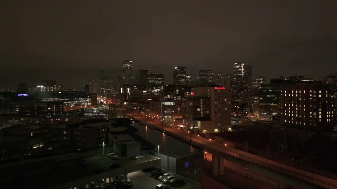 Aerial reveal of night view of Denver Colorado skyline from behind apartment building