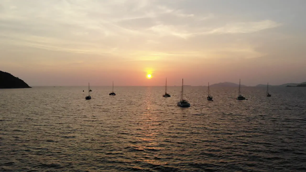 Backward flight over the sea with sunset and boats on the background