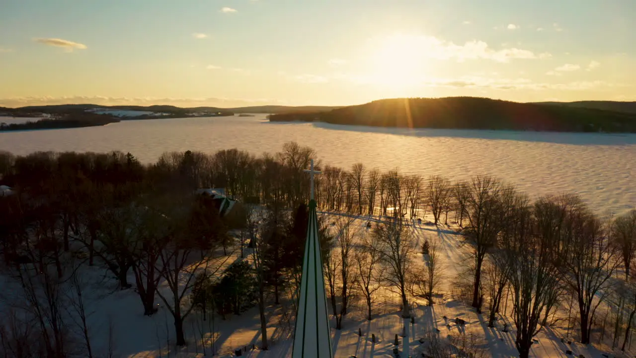 Picturesque winter aerial view of a church steeple against the light of the setting sun