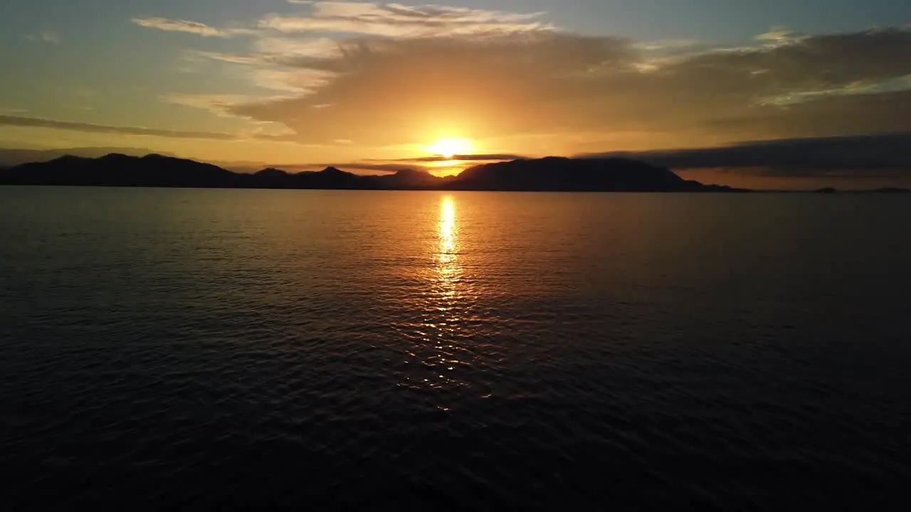 A gorgeous sunrise by the ocean looking at the coast and the sun from a boat