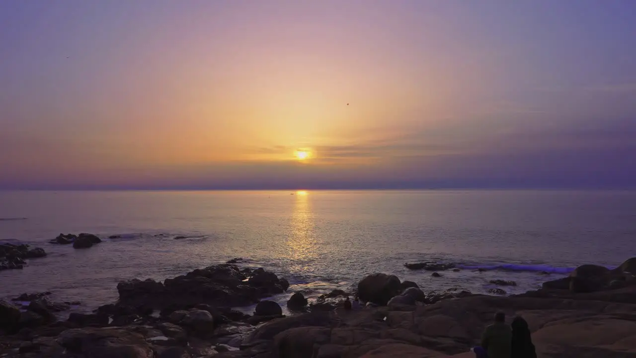 Couples watching sunset at a rocky beach in Vila Nova de Gaia Porto Portugal