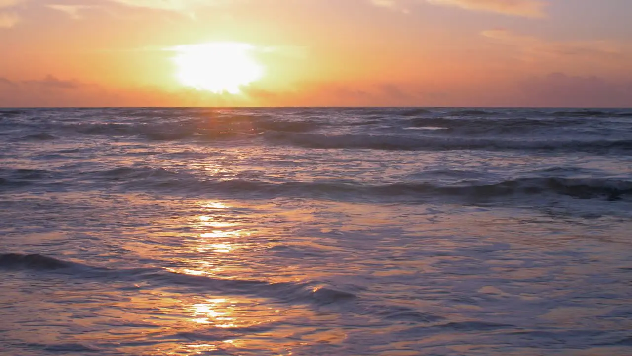 Beautiful sunset on the background of Baltic sea sun going beyond the horizon illuminating water and clouds in the sky calm sea waves romantic mood copy space low wide shot