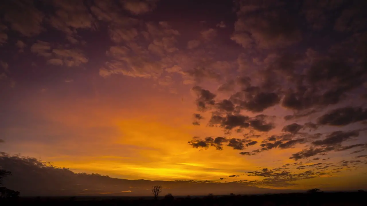 Stunning sunrise timelapse over African plains with mountains and red sky clouds illuminated