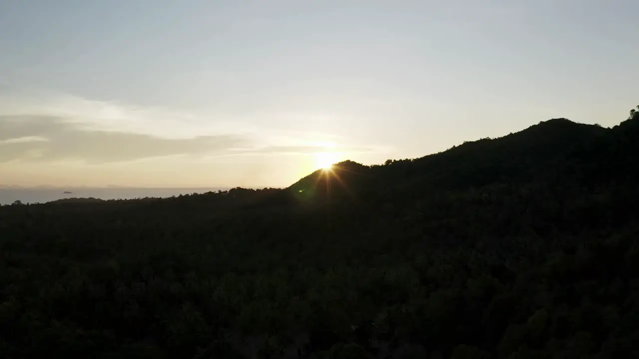 Bright sunshine emerges from edge of mountain on Koh Phangan sunset