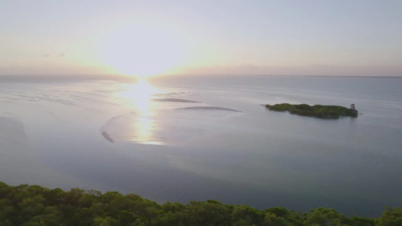 Drone view of beach with bright sky and sun