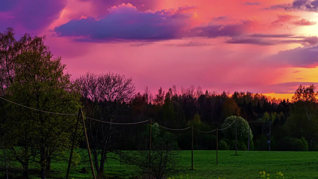 Time lapse of a fiery sunset with fast moving clouds over a green nature landscape