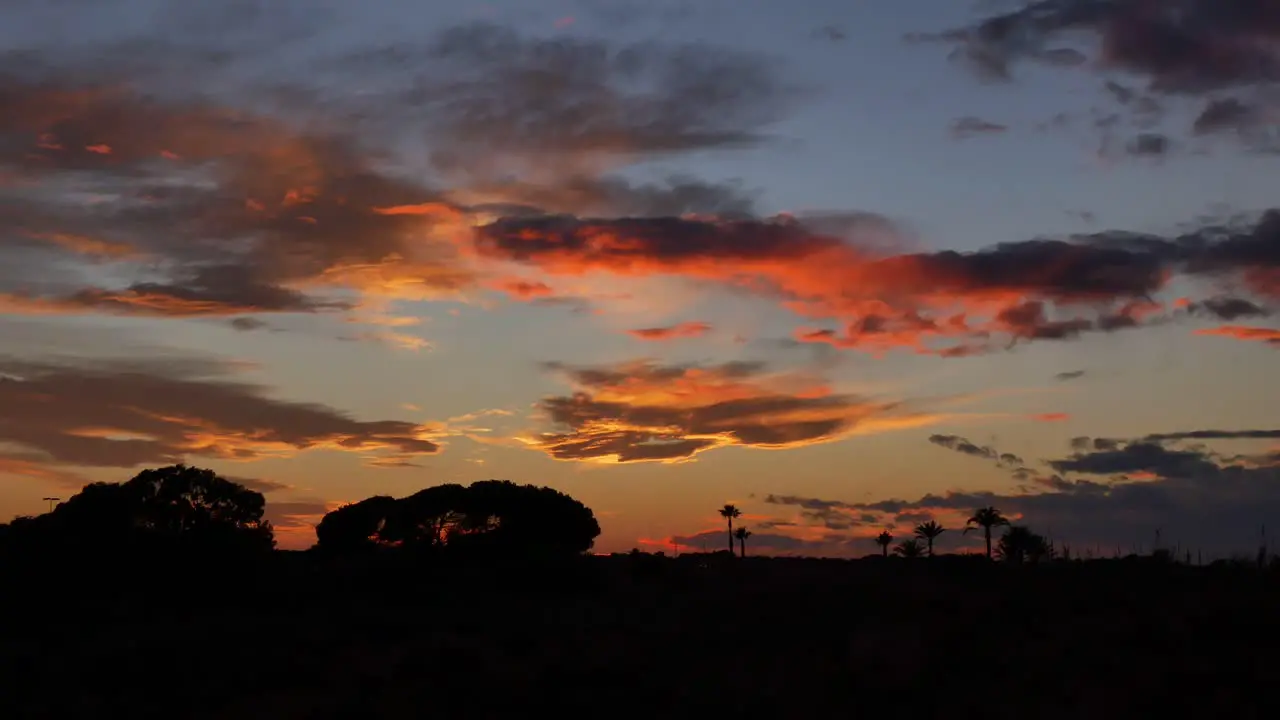 Clouds at different levels and colours moving over trees