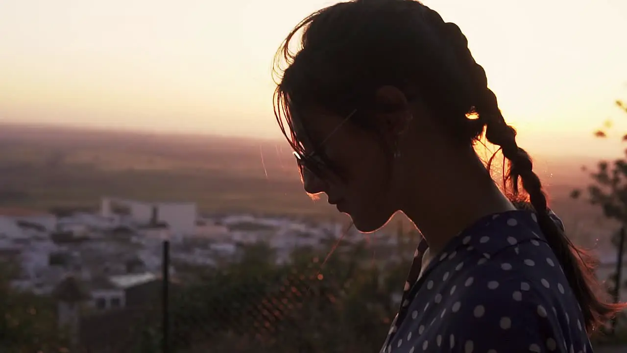 model fixing her hair with a vibrant sunset behind over the valley