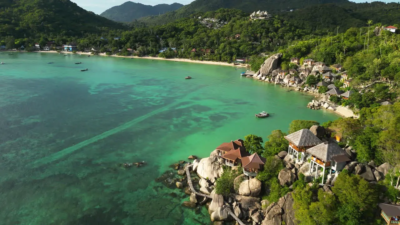 Koh Tao south east Asia tropical paradise with sand beach and pristine ocean clear water sea drone revealing bay with beach resort luxury accommodation above the rocky cliff