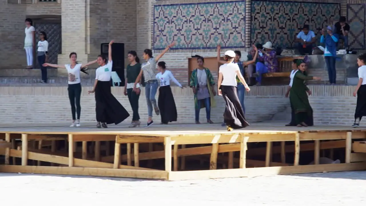 Young women rehearse for Silk and Spices Festival in front of Kalon mosque in Bukhara Uzbekistan