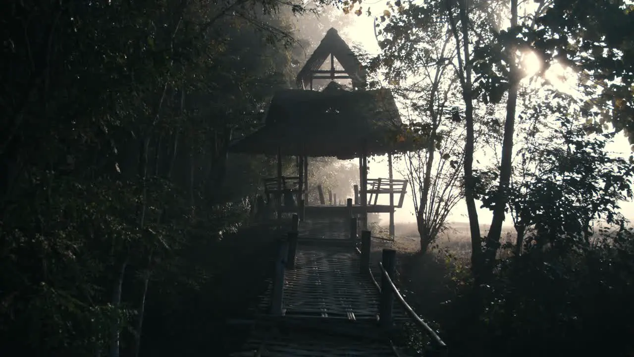 A bamboo bridge and hut in the mist next to rice fields in Thailand