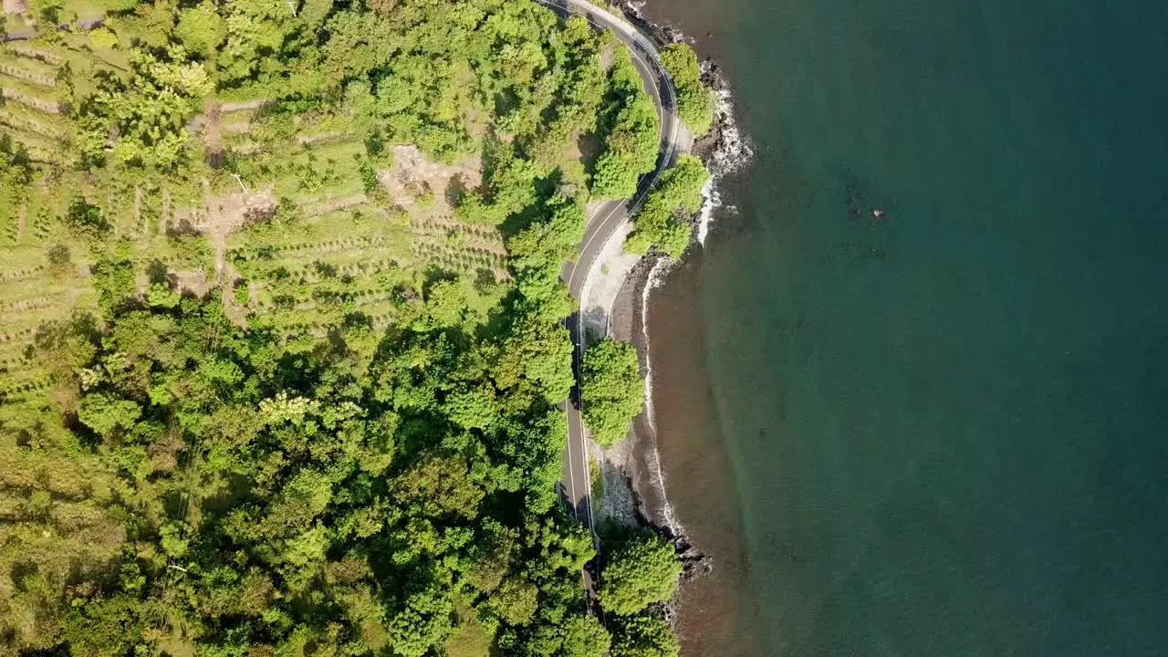 bird eyes view and flying straight via drone over the highway beside the beach in Bali 4K and 30 fps