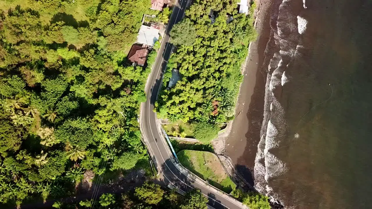 Bird eyes view of flying up via drone over the highway beside the beach in Bali 4K and 30 fps