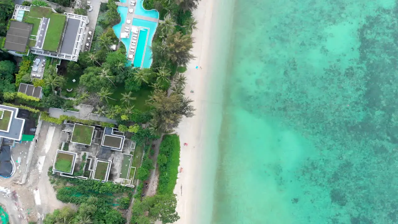 Panning from the bottom going up while doing an overhead drone shot of the resorts at Tri Trang Beach located in Phuket island in Thailand