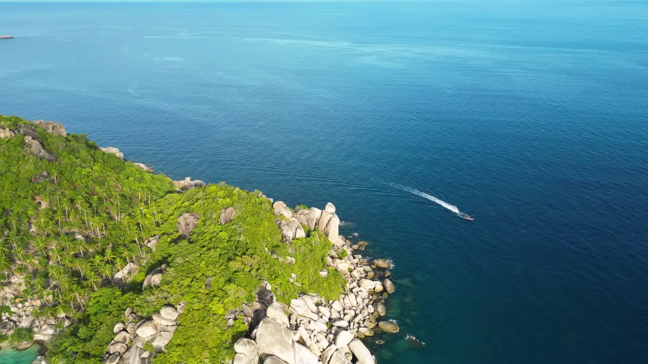 Aerial of ferry boat vessel overtaking corner of cliffy coast of koh tao Thailand south est asia famous travel destination for scuba diving course