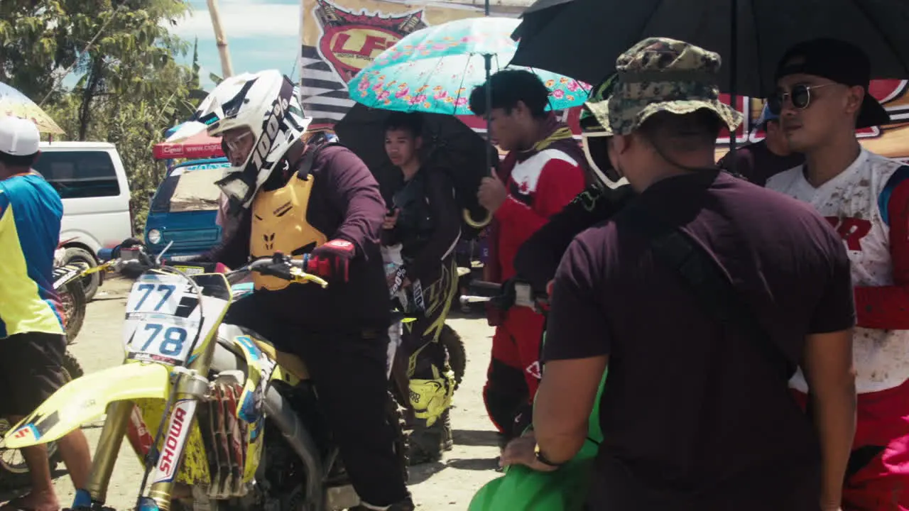 Participants and their staff exchange conversations while awaiting their turn as day 2 of motocross competition has begun