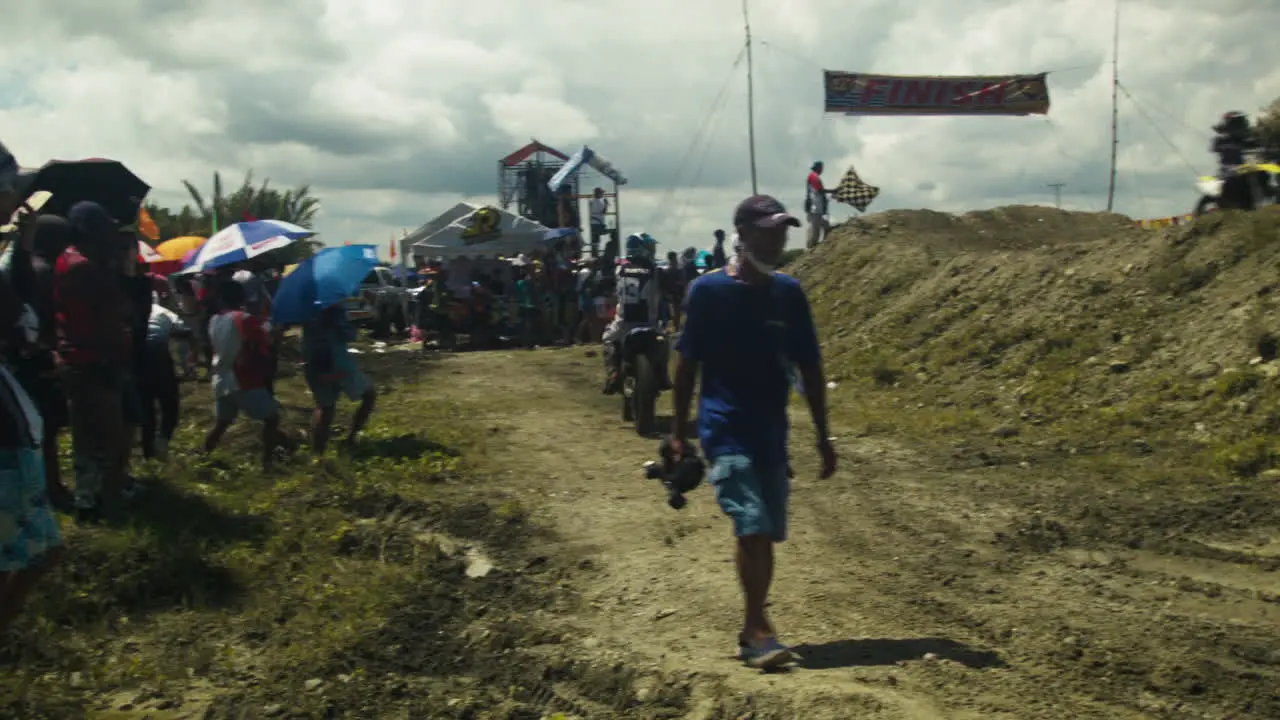 Onlookers participants and the media pass by near the race track as the highly anticipated motocross competition is about to begin