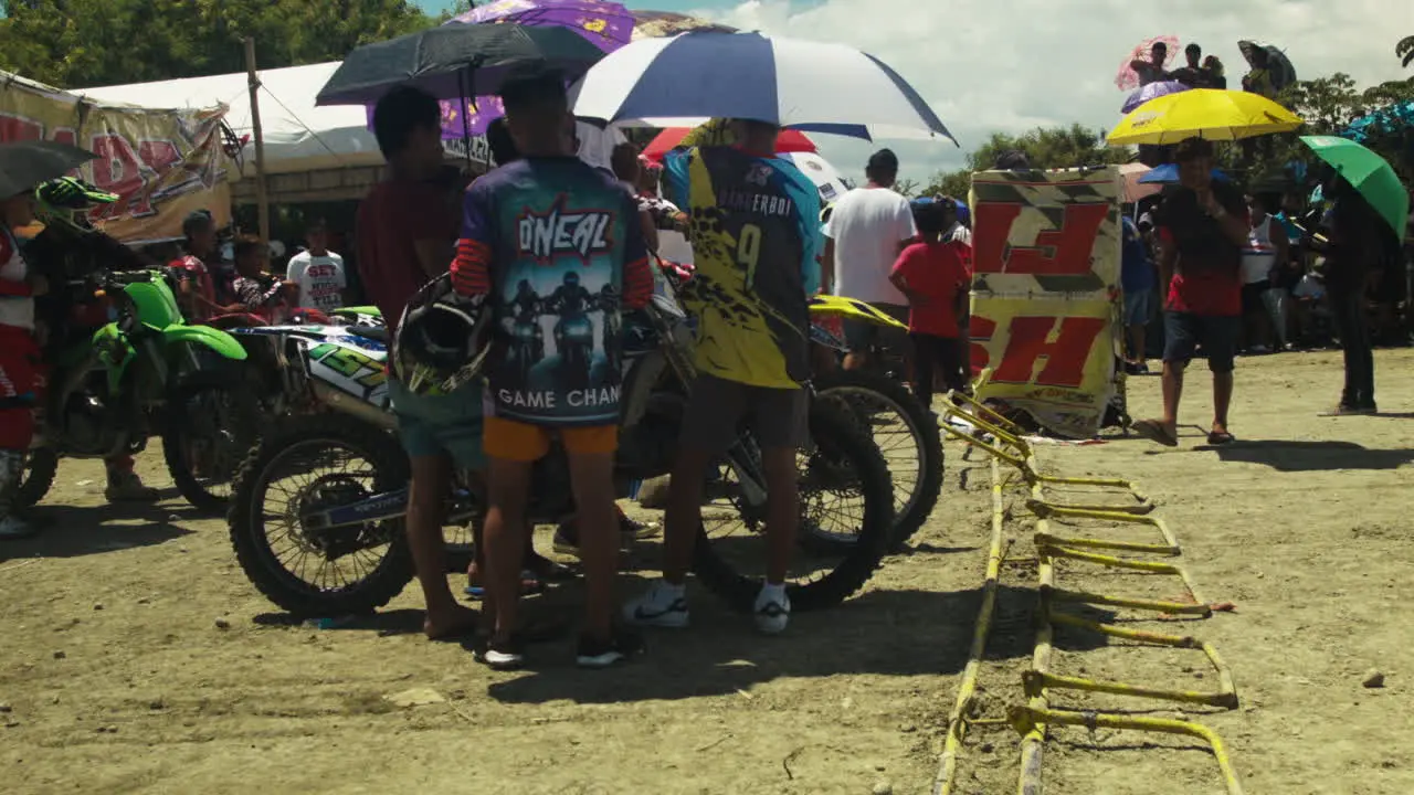 Umbrellas for participants everywhere as the 1st motocross competition since the pandemic is graced by unforgiving heat