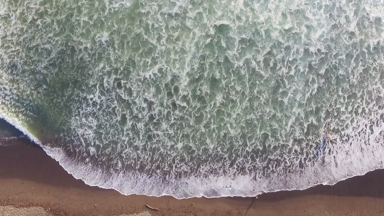 Aerial Drone Shot Of Ocean Waves Rolling And Crashing Into Sandy Beach