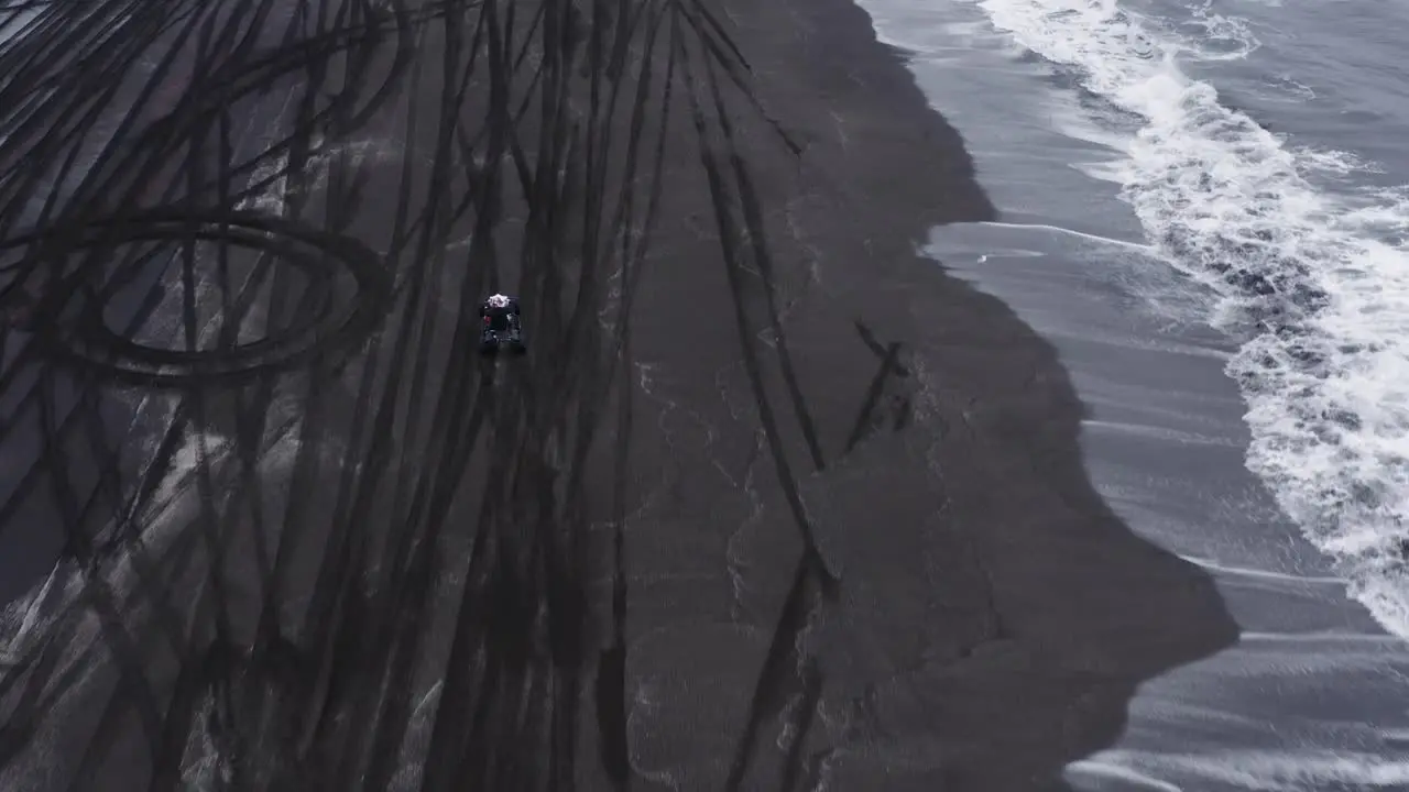 Man on quad bike accelerating and pulling wheelie on black beach in Iceland