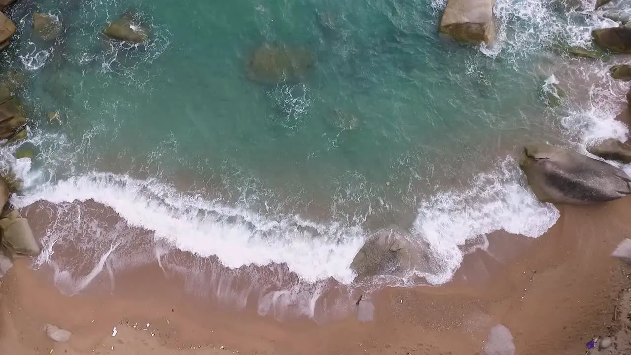 Mild wave washing beach over bay continuously overlooking dronefly static shot