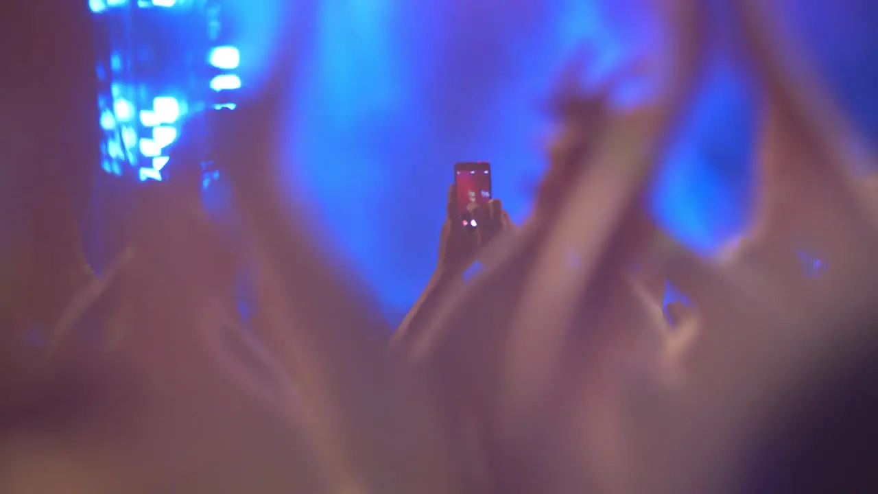 A slow motion of a crowd clapping hands at a concert show