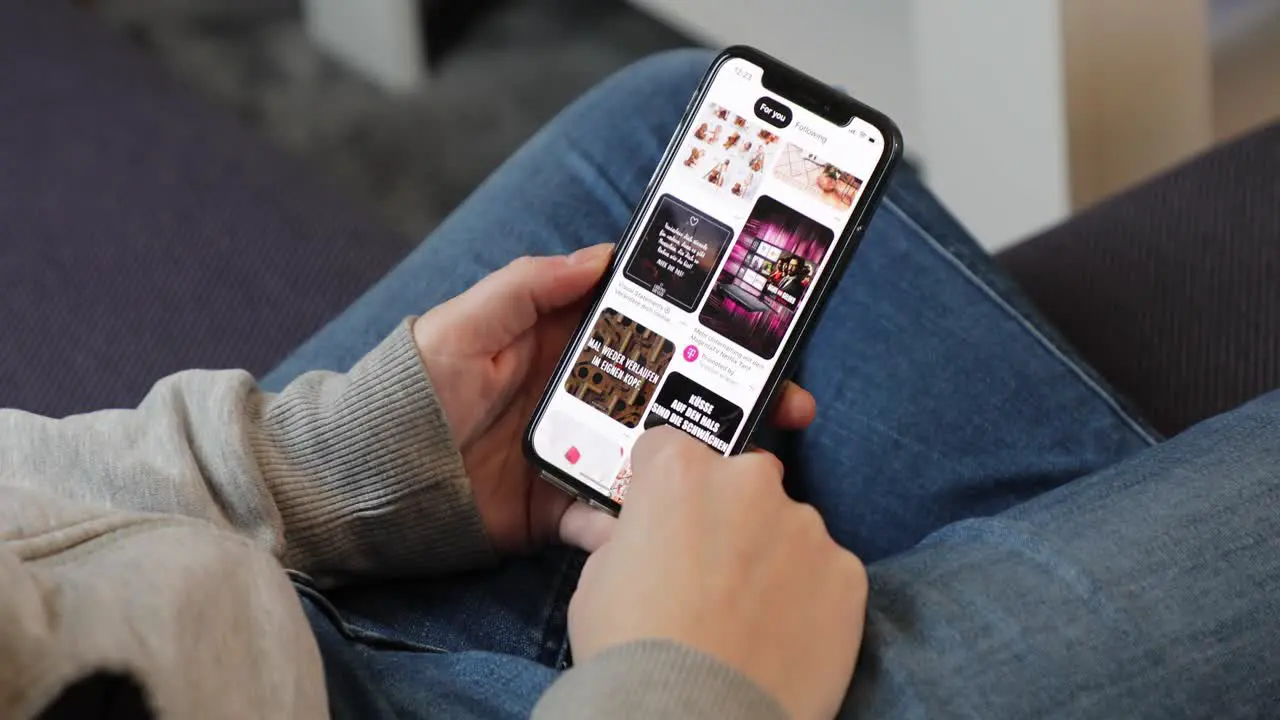 Young woman using Pinterest app on an iPhone in casual home environment