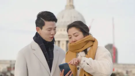 Young Asian Couple On Holiday Walking Across Millennium Bridge With St Pauls Cathedral In Background 1