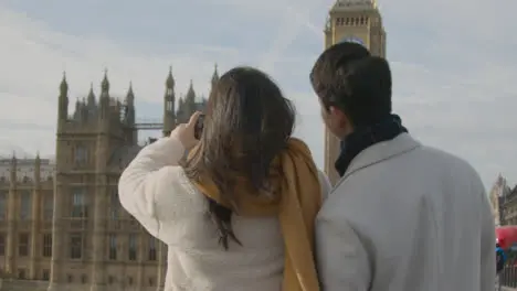 Young Asian Couple On Holiday Posing For Selfie In Front Of Houses Of Parliament In London UK 4